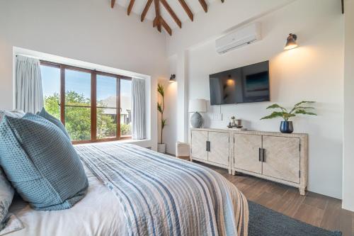 a bedroom with a bed and a tv on a wall at Conch Shell Cottage and The PoolClub at Mahogany Bay! in San Pedro