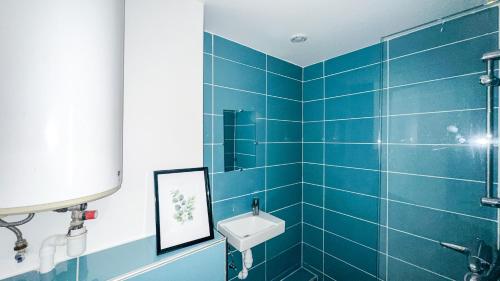 een blauwe betegelde badkamer met een wastafel en een douche bij Le Color Spot - Porte de Paris in Pantin