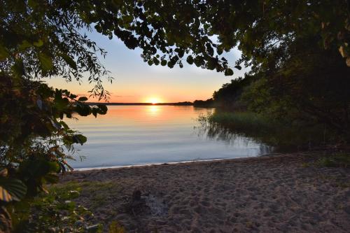 a sunset on the shore of a lake at Dadaj Park Home in Biskupiec