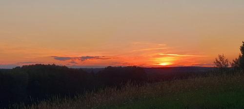 a sunset over a field with trees and grass at Dadaj Park Home in Biskupiec