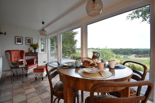 a dining room with a wooden table and a large window at Dadaj Park Home in Biskupiec