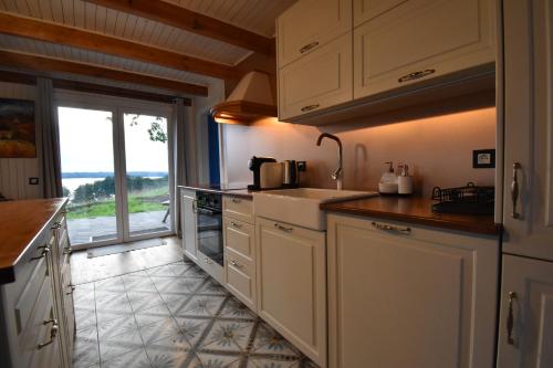 a kitchen with white cabinets and a sink and a window at Dadaj Park Home in Biskupiec