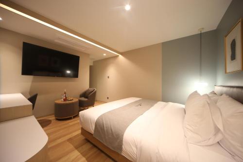 a hotel room with a bed and a flat screen tv at Dongnae Hound Hotel Sajik Minam Station in Busan