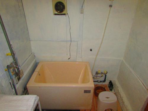 a small bathroom with a tub and a toilet at ゲストハウス杉田 古民家貸切の完全プライベート空間 杉田駅徒歩2分 セルフチェックイン in Yokohama