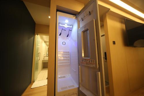 a room with a refrigerator with a television and a bathroom at Hound Hotel Minam in Busan