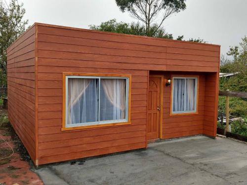 a small house with two windows and a door at Cabaña Queule in El Crucero