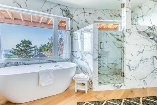 y baño con bañera blanca y ducha acristalada. en Summit Lighthouse - Meredith Lodging, en Pacific City