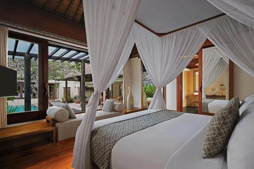 a bedroom with a white bed with curtains at Amarterra Villas Resort Bali Nusa Dua, Autograph Collection in Nusa Dua