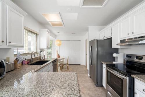 a kitchen with white cabinets and a stainless steel refrigerator at Gilbert Getaway - pool+games+pool table in Gilbert