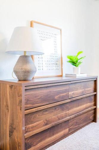 a lamp on top of a wooden dresser with a picture at Gilbert Getaway - pool+games+pool table in Gilbert