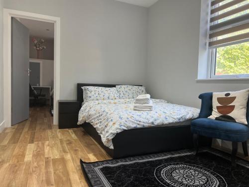 1 dormitorio con 1 cama y 1 silla azul en MJ Serviced Apartment up to 6 Guest - Luxurious living in West London next to Tube station & Central London en Hanwell