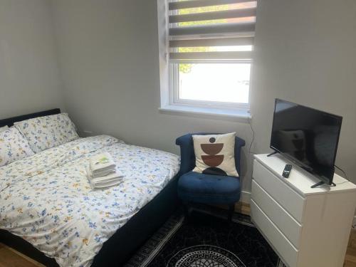 1 dormitorio con 1 cama, TV y silla en MJ Serviced Apartment up to 6 Guest - Luxurious living in West London next to Tube station & Central London, en Hanwell