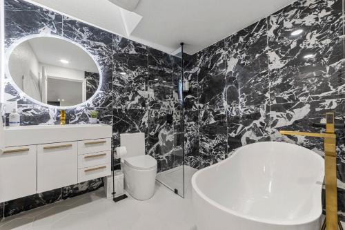 a black and white bathroom with a sink and a mirror at NEW Fully Remodeled, Updated 8 beds, 3 baths High End Modern Home Private WaterFront in Kirkland