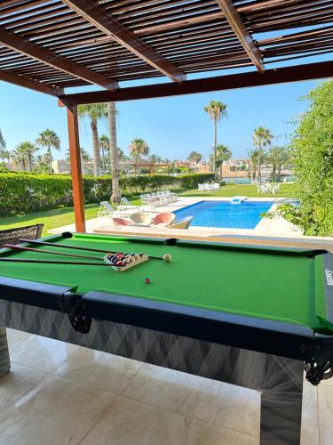 a pool table in front of a swimming pool at فيلا للايجار مارينا 5 الساحل الشمالي in El Alamein