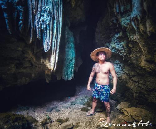 a man wearing a straw hat standing in a cave at Gratum Beach Resort in Dapitan