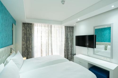 a hotel room with a white bed and a mirror at Protea Hotel by Marriott Cape Town North Wharf in Cape Town