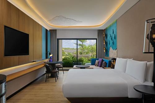 a hotel room with a large bed and a tv at Renaissance Bali Nusa Dua Resort in Nusa Dua