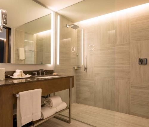 a bathroom with a shower and a sink and a mirror at Hilton Garden Inn Chihuahua in Chihuahua