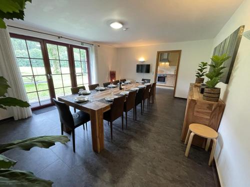 uma grande sala de jantar com uma mesa longa e cadeiras em Ardennes villa with riverside garden and views em Atzerath