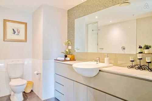 a bathroom with a sink and a toilet and a mirror at HeartCBD LUX Top Floor 2 Bedroom /Pool/Spa/GYM in Melbourne