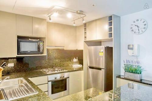 a kitchen with a refrigerator and a clock on the wall at HeartCBD LUX Top Floor 2 Bedroom /Pool/Spa/GYM in Melbourne