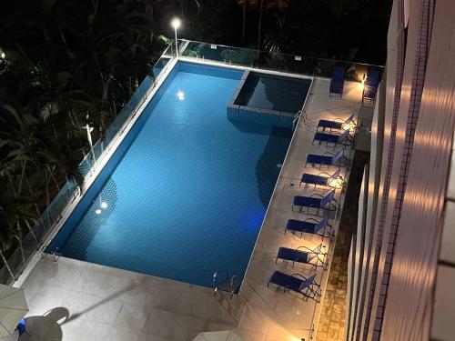 una vista aérea de una piscina por la noche en APTO RIVIERA 2 DORMS COM AR A 180 m DA PRAIA ! APROVEITE AS BAIXAS TARIFAS DE MAIO ! CONSULTE !, en Riviera de São Lourenço