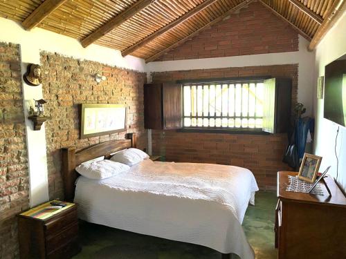 a bedroom with a bed and a brick wall at Finca Cafetera Madrigal - Café Sortiz in Maravélez