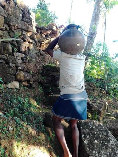 a person standing on a rock with a bucket on his head at Hamadhi guest in Haldummulla