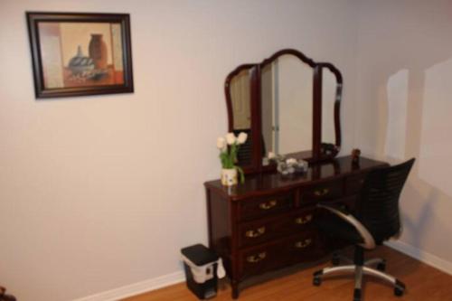 a bedroom with a dresser and a chair and a mirror at Leila`s place-Basement apartment in private home in Gatineau