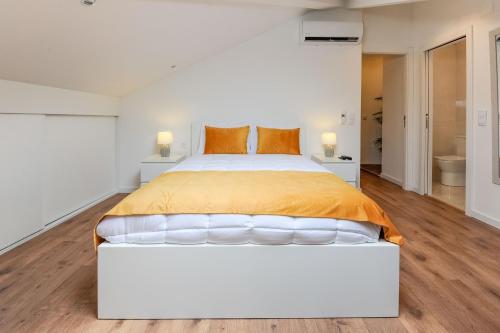 een witte slaapkamer met een groot bed met oranje kussens bij Boutique Room Montijo in Montijo