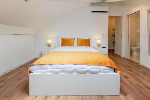 a white bedroom with a large bed with orange pillows at Boutique Room Montijo in Montijo