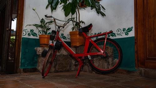 a red bike parked next to a wall with potted plants at Hotel Casa del Fraile in Morelia