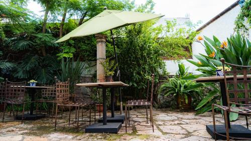a table and chairs with an umbrella in a garden at Hotel Casa del Fraile in Morelia