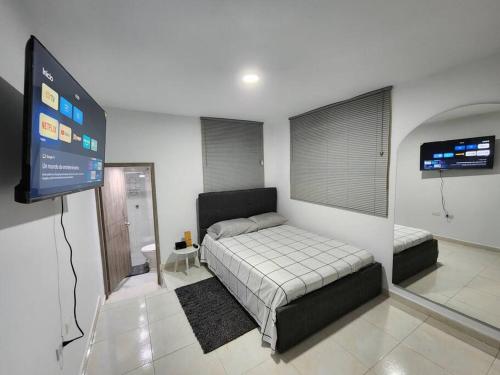 een slaapkamer met een bed en een flatscreen-tv bij Apartamento céntrico con suave cama y wifi gratuito! in Cali