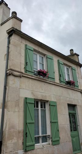 un edificio con finestre con persiane verdi e fiori sopra di L'esprit de famille a Semur-en-Auxois