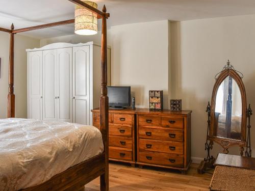 Schlafzimmer mit einem Bett und einer Kommode mit einem TV in der Unterkunft Brookside Cottage in Copley