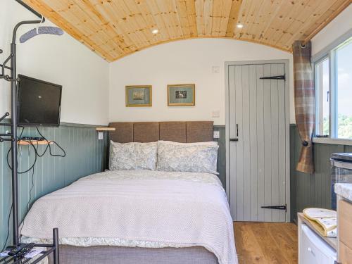 a bedroom with a bed and a tv and a window at Partridge Hut-uk44850 in Walton