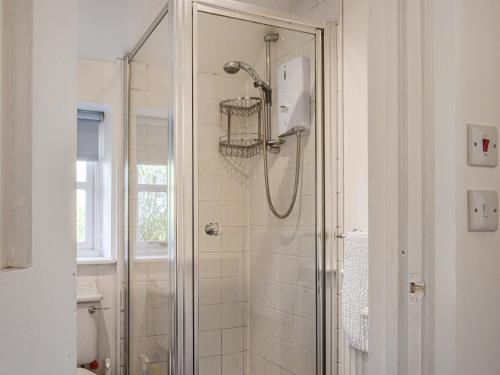 um chuveiro com uma porta de vidro na casa de banho em No Place em Sennen