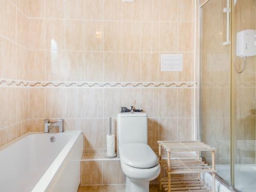 a bathroom with a white toilet and a bath tub at Yare Cottage in Reedham