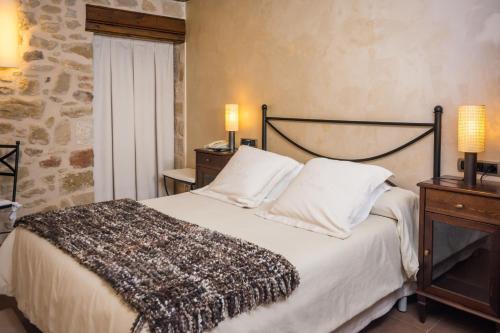 Hotel Villa de Cretas في Cretas: غرفة نوم بسرير وطاولة بها مصباحين
