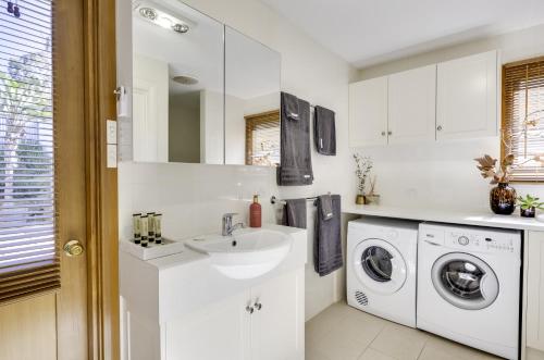 a white bathroom with a sink and a washing machine at Seascape Retreat in Victor Harbor