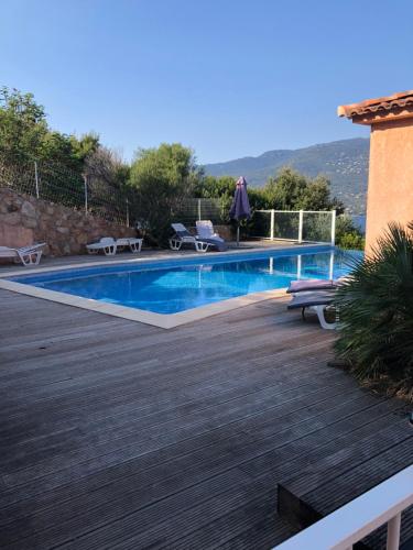 une piscine avec une terrasse en bois à côté d'une maison dans l'établissement punta di buturetu, à Propriano