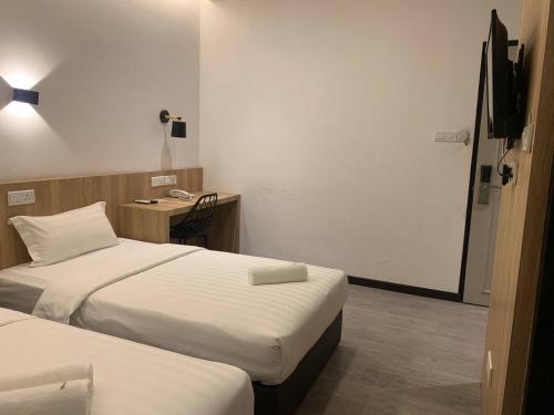 Habitación con 2 camas y escritorio con teléfono. en The Daily Hotel, en Kota Kinabalu