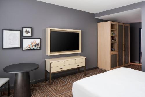 a bedroom with a tv and a table and a stool at Trilith Guesthouse, Fayetteville, GA, a Tribute Portfolio Hotel in Fayetteville