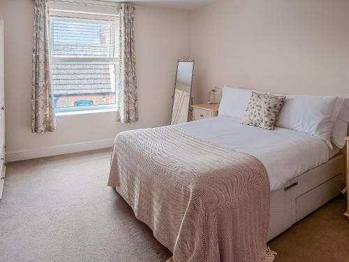 a white bedroom with a bed and a window at Oakleigh By The Sea in Cromer