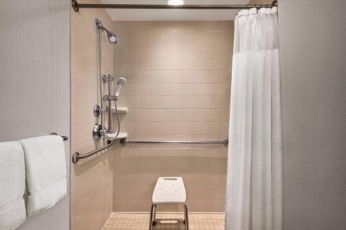 een douche met een douchegordijn en een kruk in de badkamer bij Courtyard by Marriott Madison West / Middleton in Middleton
