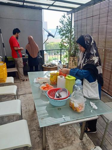 Una mujer sentada en una mesa con comida. en Sky Chalet at Axis Next To LRT Pandan Indah Ampang, en Ampang
