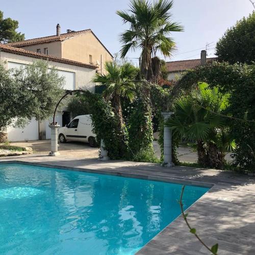 une piscine bleue dans une cour avec des palmiers dans l'établissement Magnifique haut de villa au calme absolu a 10 minutes des plages, à La Bouilladisse