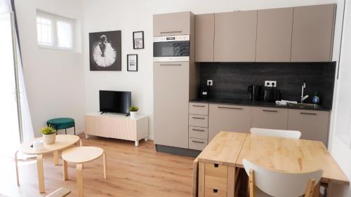 une cuisine avec des armoires blanches et une table en bois dans l'établissement Centre Cannes, Le Grand Turkheim By Palmazur Vacances, à Cannes