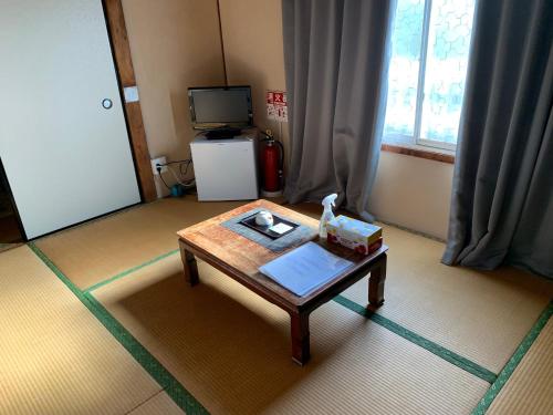 a living room with a coffee table and a television at 2F SAKURA RIVER HOUSE, yao 桜と川の家 2F in Yaochō